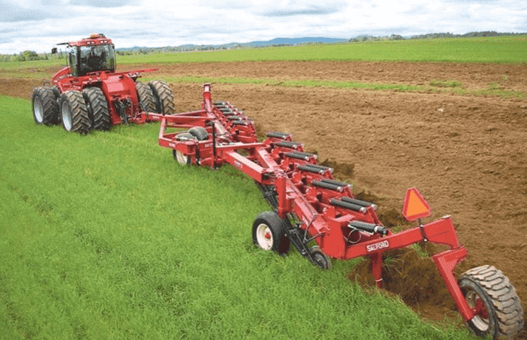 A tractor pulls a modern plow through the field.