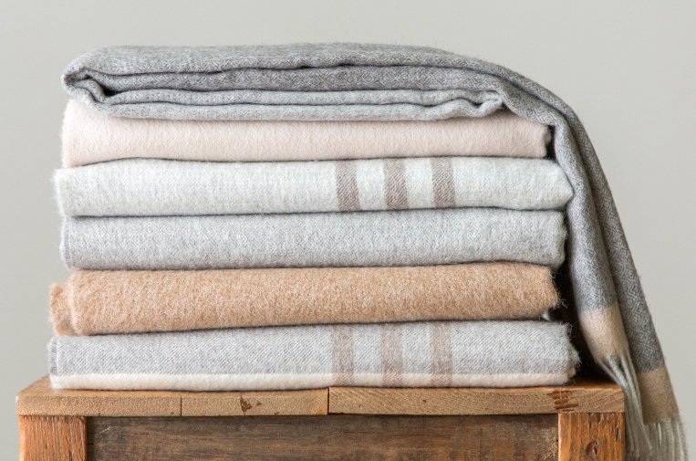 A stack of blankets made out of alpaca wool sit on a table.