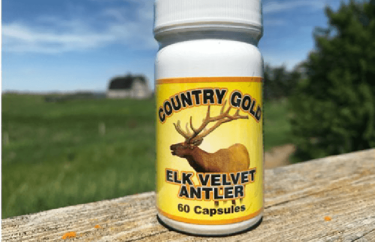 A bottle of dietary supplements made from elk antler sits on a fence ledge.