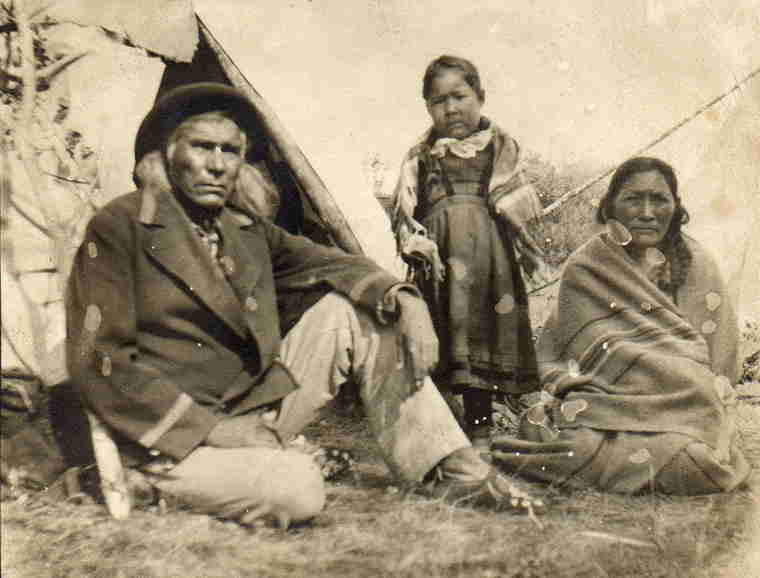 A photograph of an Indigenous man, woman and child outside their teepee.