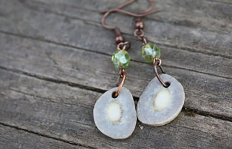 A pair of earrings that has been made from elk antlers sit on a wooden table.