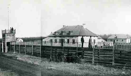 A photograph of the Fort Pelly trading post in 1887. Two non-Aboriginal couples are posing for a photo, standing on top of the new plank fence palisade.