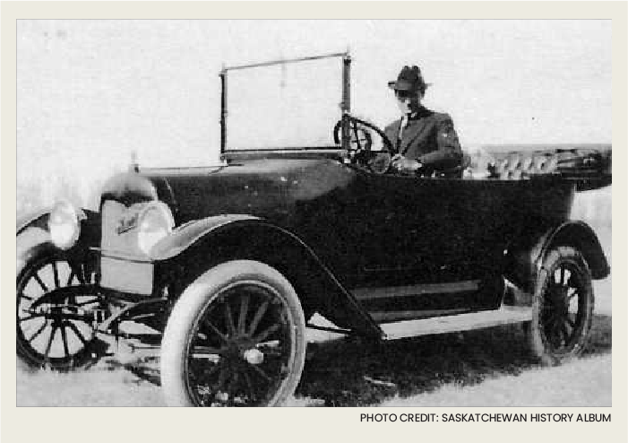 Past-Transportation-Vehicles1 (SaskHistory) A man with a suit and a hat are sitting in a car that has an open cab on it.