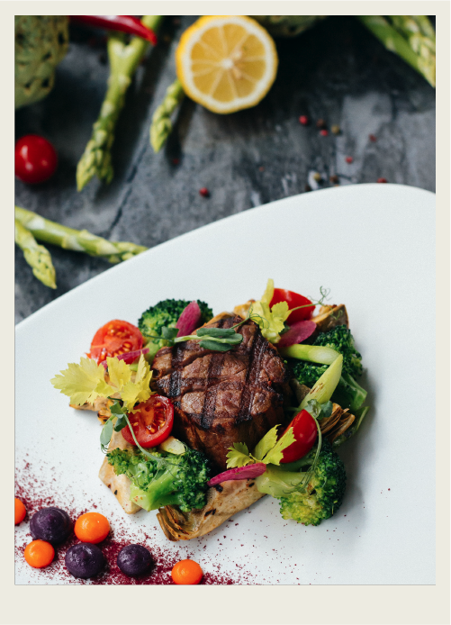 A steak with some roasted vegetables are shown on a plate. 