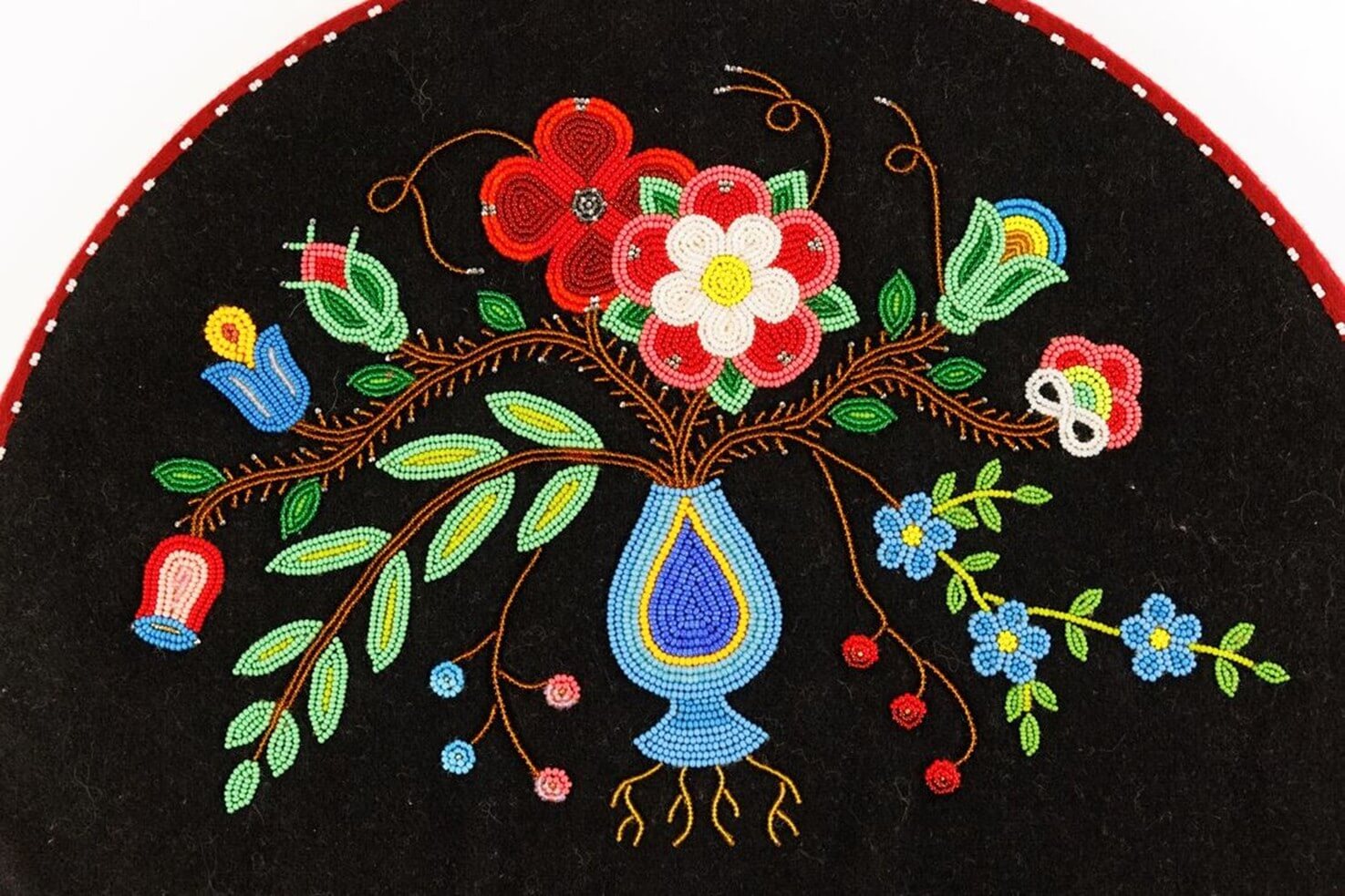 A piece of art by Leah Marie Dorion made with mosaics shows two Indigenous women facing each other with their hair blowing out behind them. There is a sun with butterflies in the centre, and snakes underneath the ground.